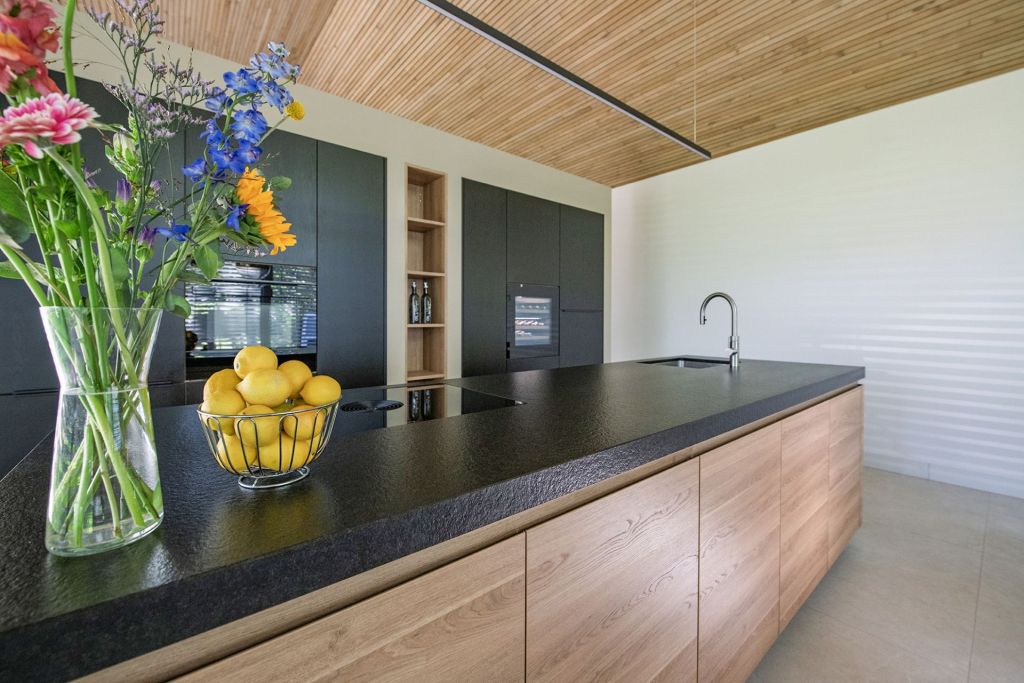 Moderne keuken met zwart stenen kookeiland, houten kasten
